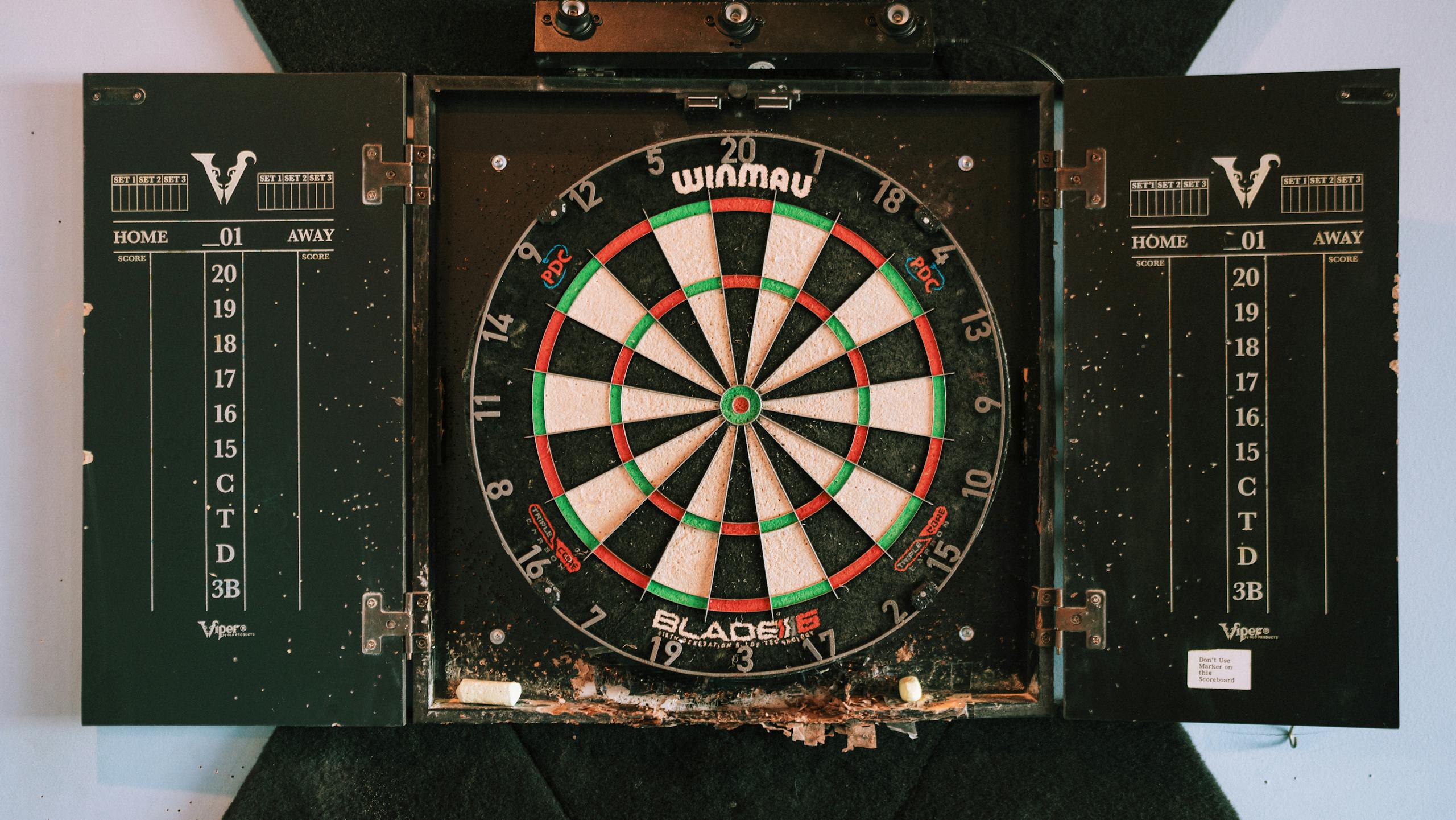 Dartboard with detailed scoreboards in a vintage setting, perfect for game rooms.